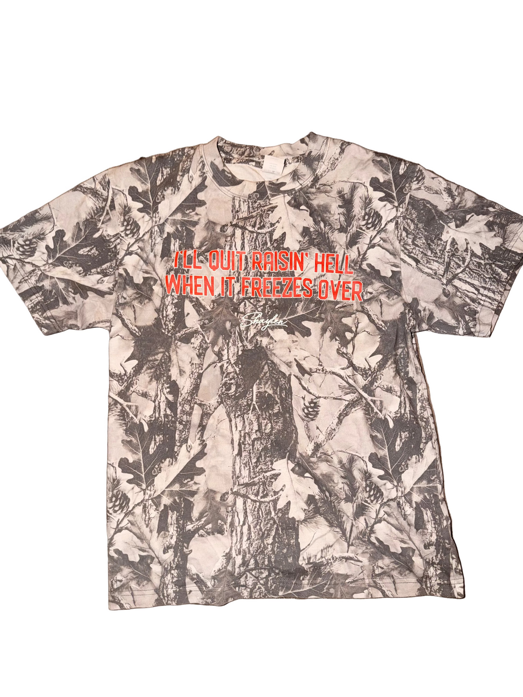Camouflage-patterned t-shirt with text on a wooden surface