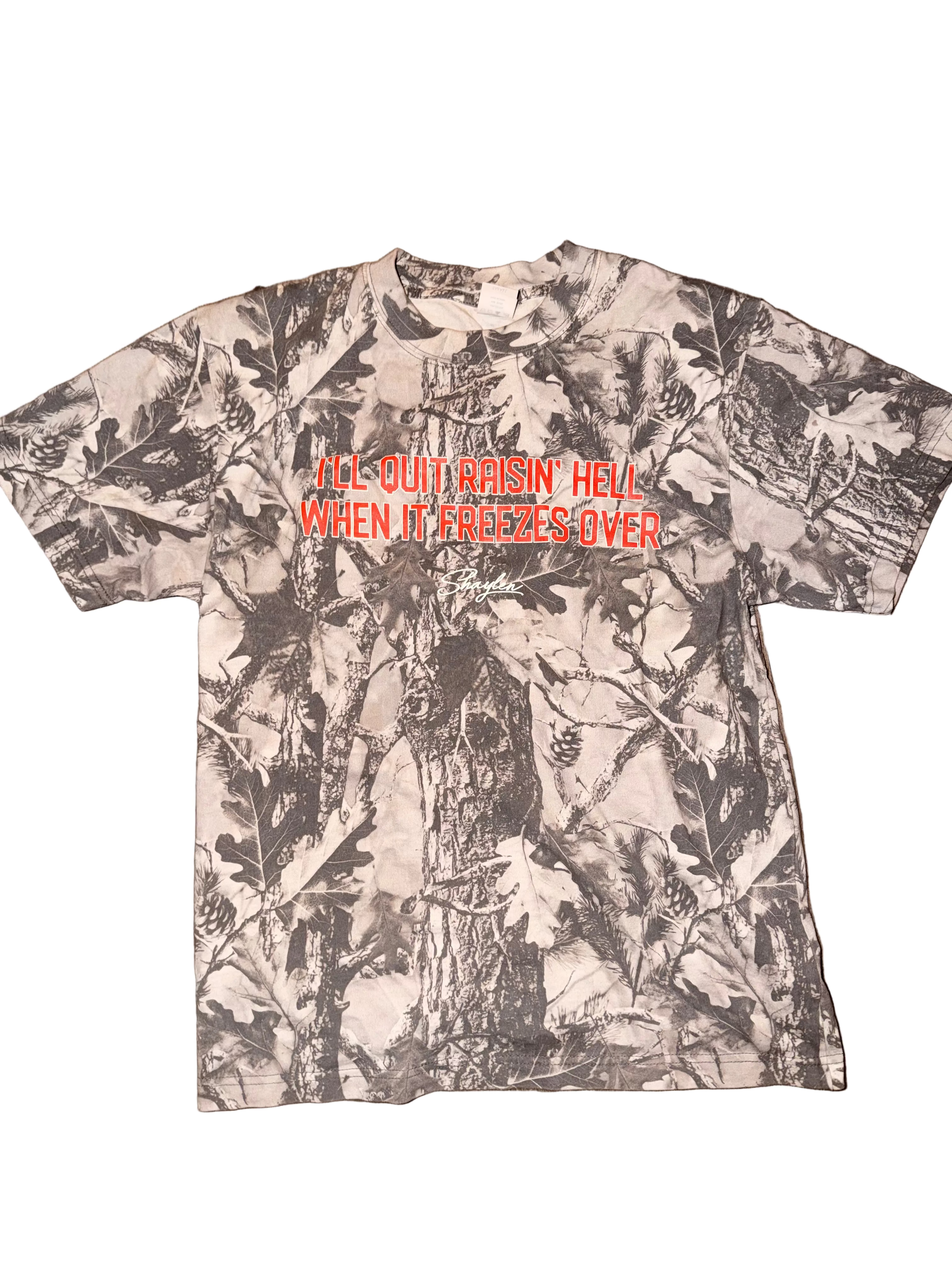 Camouflage-patterned t-shirt with text on a wooden surface