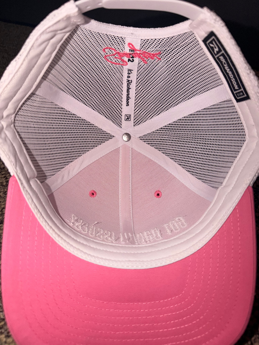 Pink cap with a mesh back and visible branding on a dark background